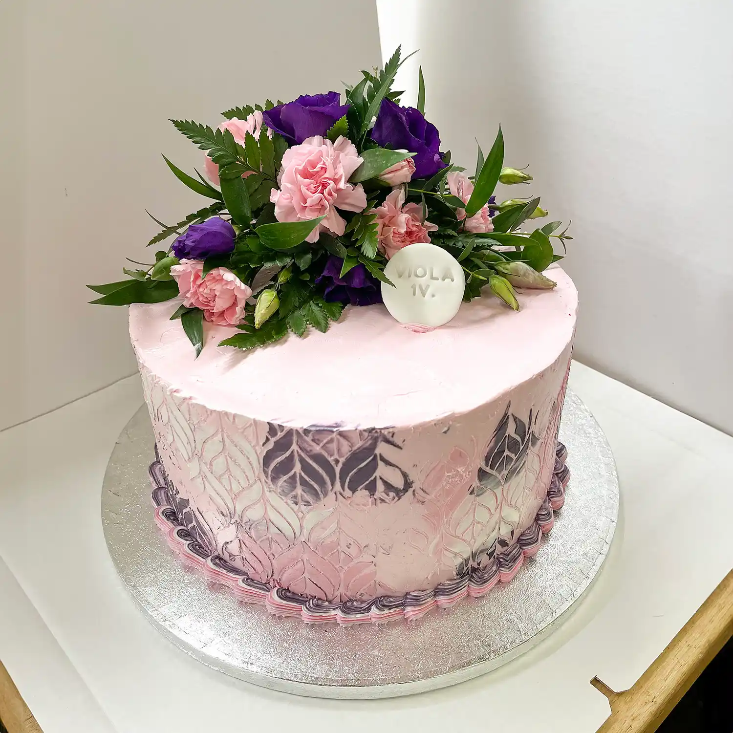 Violetti fantasiakakku kukilla koristeltuna